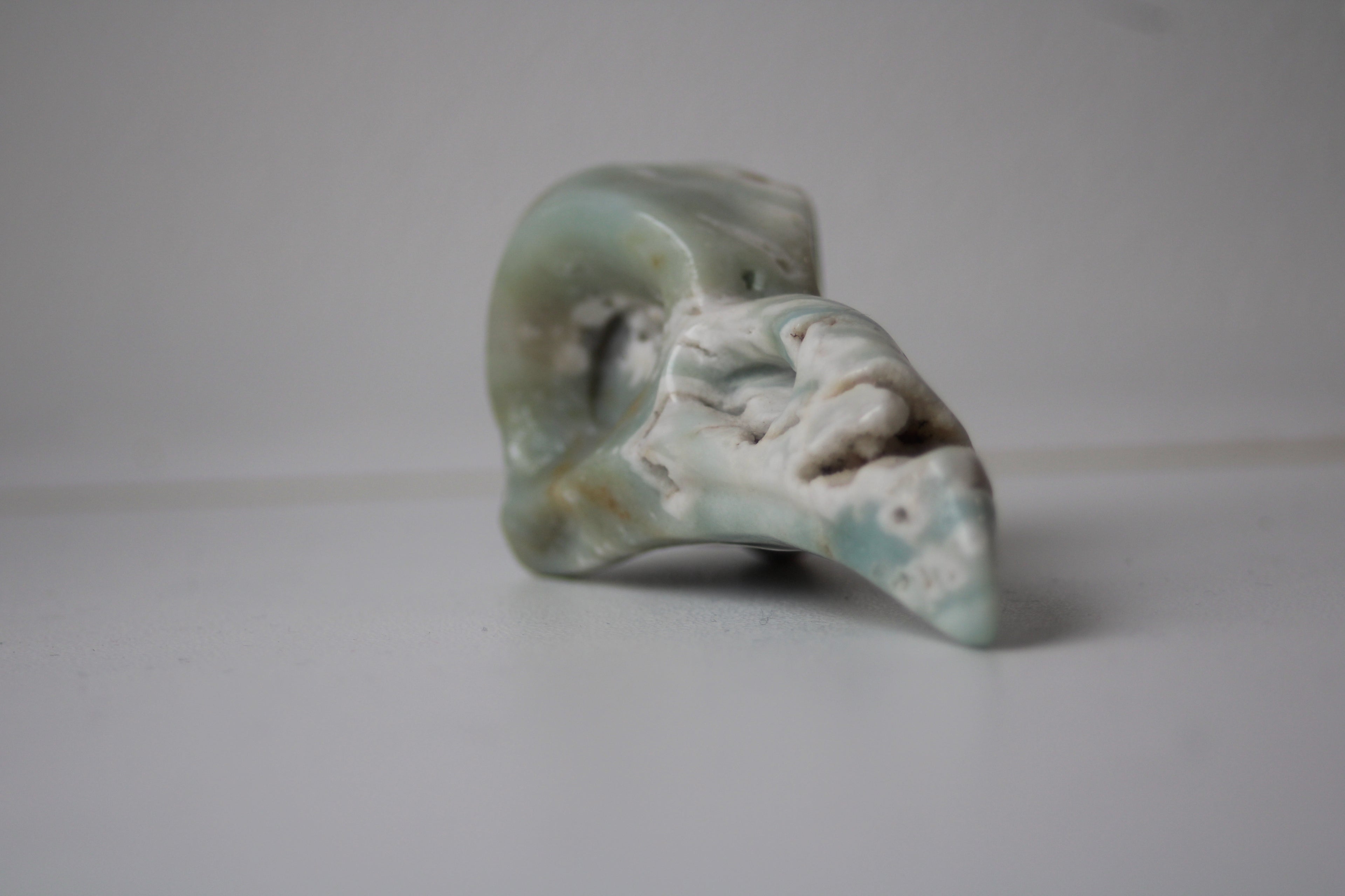 Voyagez aux confins de l'intuition avec ce crâne de corbeau en aragonite bleue, un gardien de sagesse qui diffuse une onde de sérénité absolue dans votre intérieur