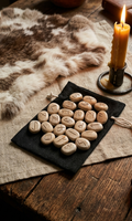 Chaque rune de ce jeu en grès pyrité, gravée à la main à l'atelier, est une pièce unique chargée d'intention, nichée dans son écrin de coton pour guider vos rituels avec la force brute de la terre.